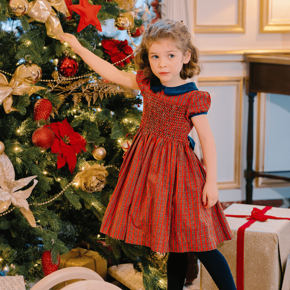 Little girl in front of Christmas tree wearing Angelica Red Tartan Dress