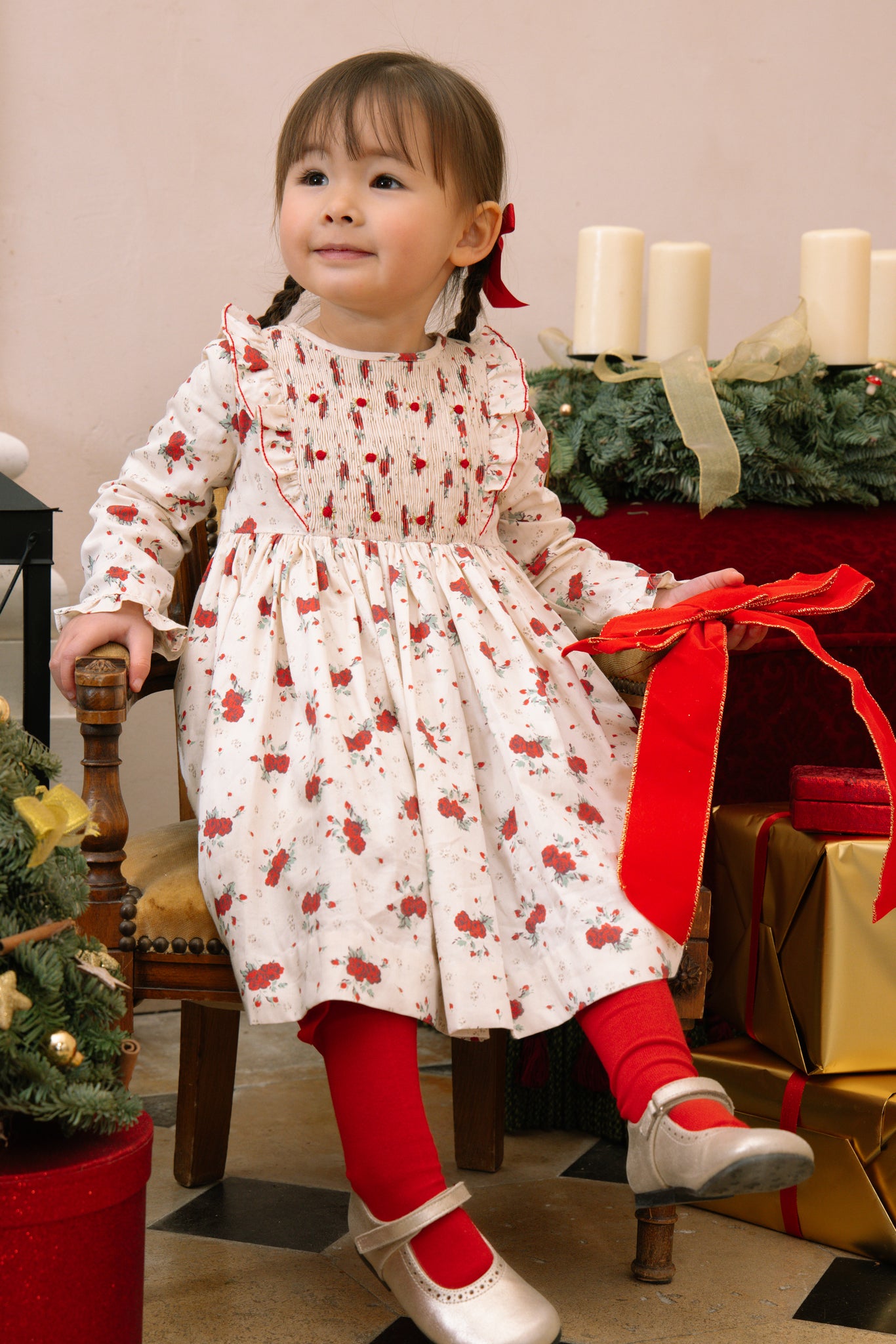 Child in Anastasia Christmas Smocked Dress sitting in front of a Christmas tree and presents.