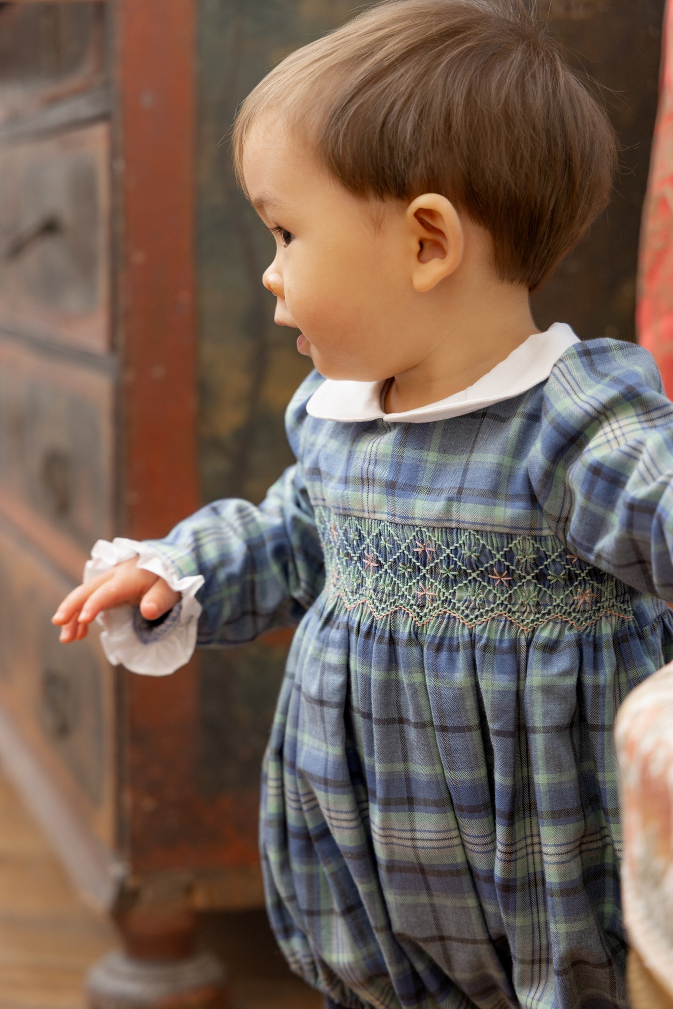 Child wearing Heidi Blue Tartan Baby Romper, standing indoors.